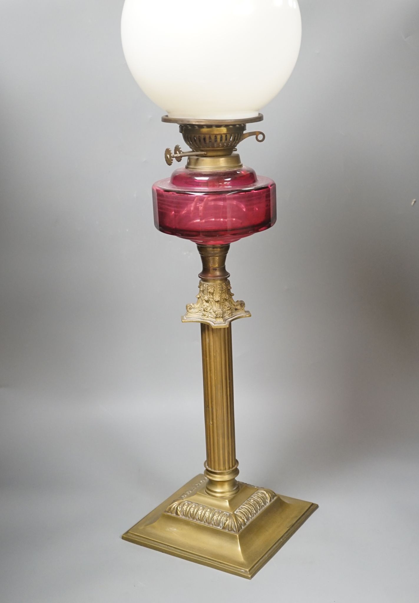 A Victorian brass and cranberry glass oil lamp, 78 cms high.